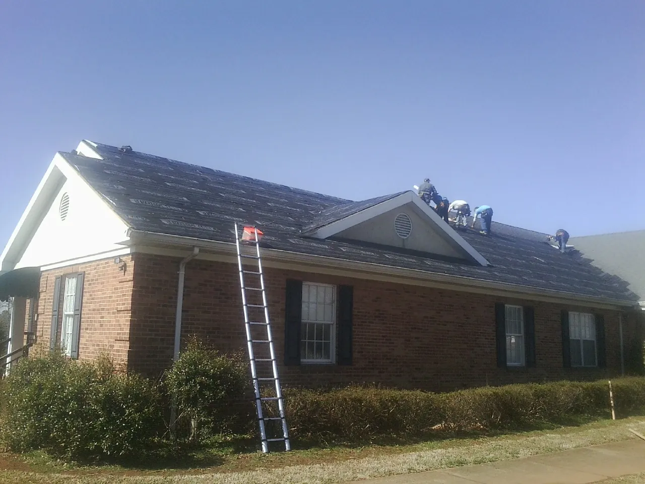 Crew tearing shingles off a brick ranch roof with a ladder set — Metal Roof Repair work by our crew in Laguna Niguel