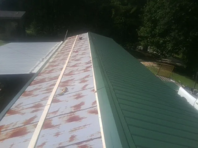 Old rusted panels beside newly installed green metal roofing — Wind Damage Roof Repair by Roofing Brothers in Laguna Niguel