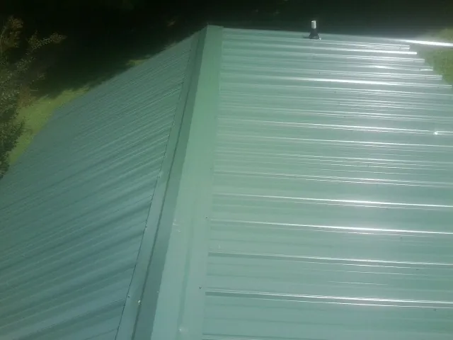 New green metal panels meeting at the ridge of a roof — Flat Roof Repair work by our crew in Laguna Niguel