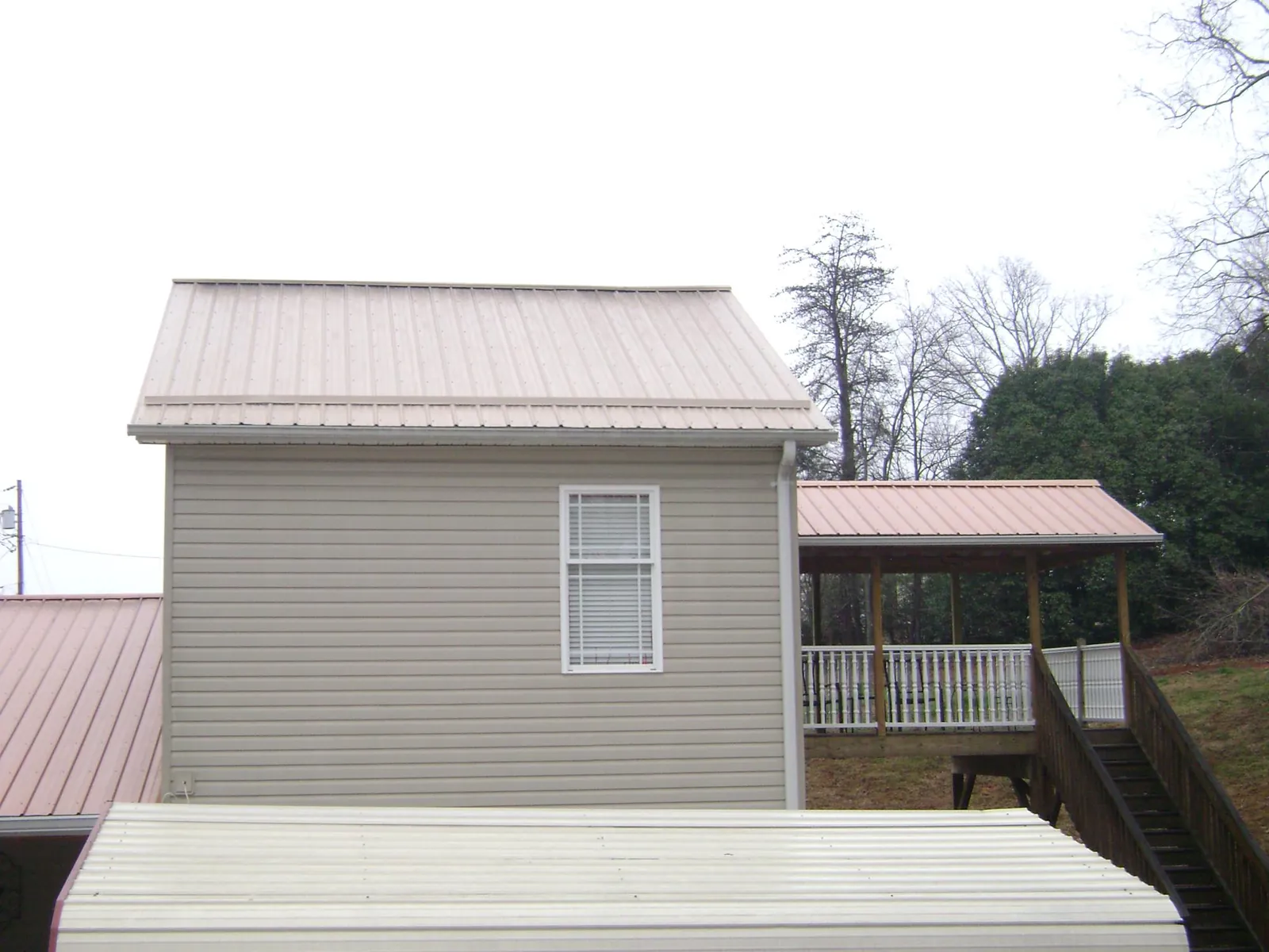 Tan metal roofs on a two story addition and attached porch, from a Roof Replacement job in Laguna Niguel
