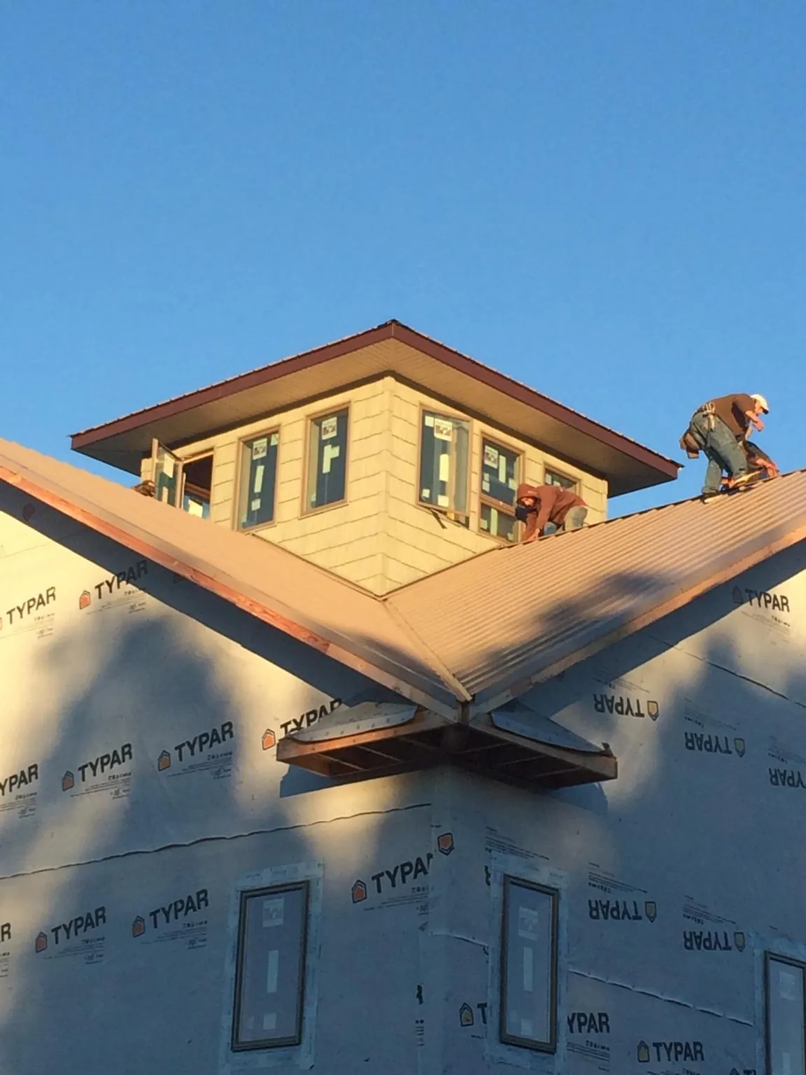 Roofers working around a rooftop cupola on a new metal roof at sunset — Roof Waterproofing in Laguna Niguel by Roofing Brothers